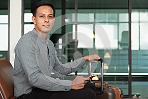 Young Asian man sitting at airport and waiting for flight