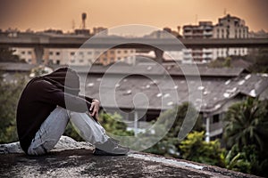 Young Asian man sitting rooftop of building with depression stress out photo