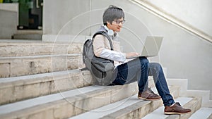Asian man university student using laptop on stair