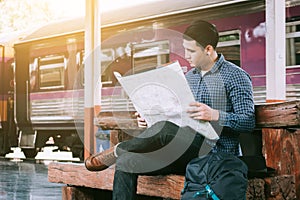 Young asian man sitting at train station and looking on map for