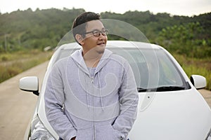 Young Asian Man Smling in Front of His Car Outdoor in Morning