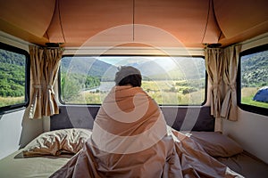 Young Asian man staying in the blanket in camper van