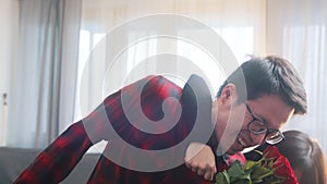 Young asian man surprising his girlfriend with bouquet of red roses