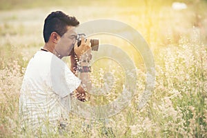 Young asian man taking photo outdoors with DSLR digital camera