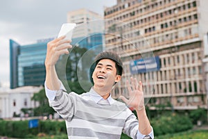 Young Asian man taking selfie on the background of city