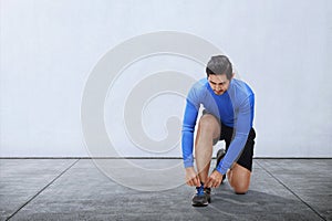 Young asian man tie sport shoe laces before running