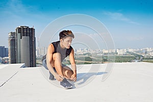 Young asian man tie sport shoe laces before running outdoors