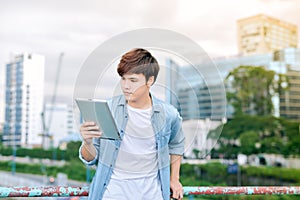 Young asian man tourist using digita; tablet outdoor in the city photo