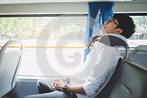 Young Asian man traveler sitting on a bus and sleeping with pillow, transport, tourism and road trip concept