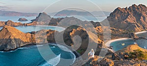 Young Asian man traveller standing on top view of Padar island in a morning sunrise in summer season, Komodo national park in