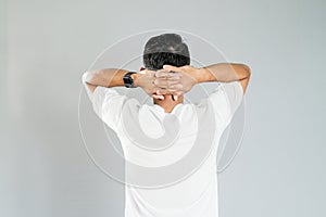 a young asian man turned around with his hands behind his head photo