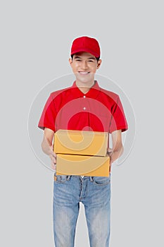 Young asian man in uniform red and cap standing carrying box stack isolated white background.