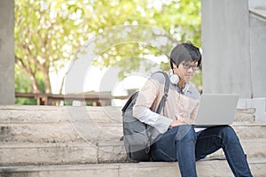 Young Asian man university student sitting on stair