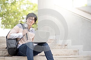 Young Asian man university student sitting on stair