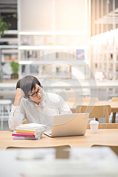 Joven asiático hombre universidad alumno en negocios en biblioteca 