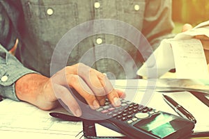 Young asian man using calculator and calculating bills in home.