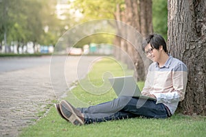 Young Asian man using laptop in the garden