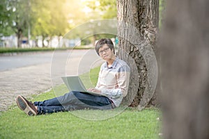 Young Asian man using laptop in the garden