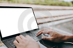 Young asian man using laptop for working and search location for travel at train station. Freelance work and travel concept