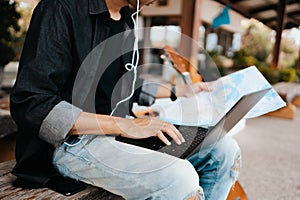 Young asian man using laptop for working and search location for travel at train station. Freelance work and travel concept