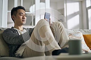 young asian man using mobile phone at home