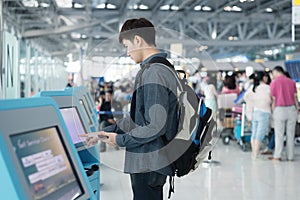 Young asian man using self check-in kiosks in airport photo