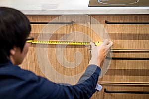 Young Asian man using tape measure for measuring furniture