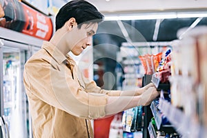 Young asian man was wondering while shopping at the convenience store at night photo