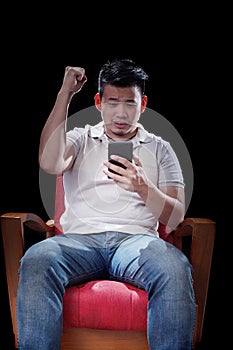 young asian man watching to smart phone screen cheer up something with exciting emotion