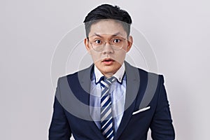 Young asian man wearing business suit and tie afraid and shocked with surprise and amazed expression, fear and excited face