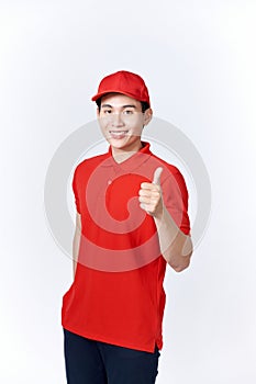 Young asian man wearing delivery uniform and cap smiling happy and positive, thumb up doing excellent and approval sign