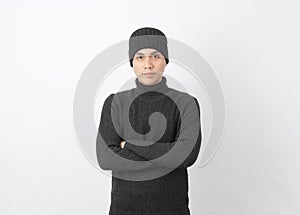 Young asian man wearing grey sweater and beanie while looking to camera with happy face on white background.