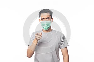 Young Asian Man wearing hygienic mask and pointing to camera with doubts face, 2019-nCoV or coronavirus.