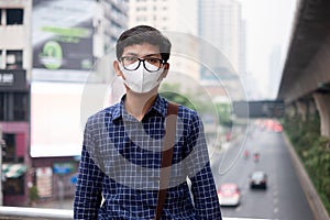 Young Asian man wearing N95 respiratory mask protect and filter pm2.5 particulate matter against traffic and dust city. photo