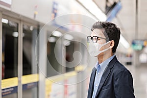 Young Asian man wearing protection mask against Novel coronavirus or Corona Virus Disease Covid-19 at public train station,is a