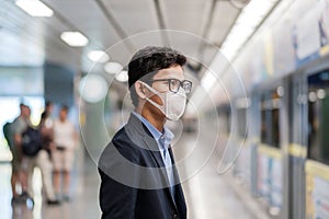 Young Asian man wearing protection mask against Novel coronavirus or Corona Virus Disease Covid-19 at public train station,is a