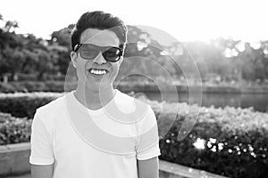 Young Asian man wearing sunglasses while relaxing at the park