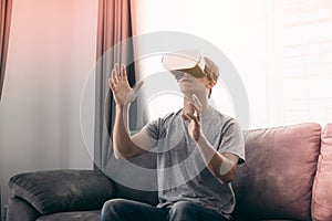 Young asian man wearing virtual reality glasses at living room for admiring virtual reality