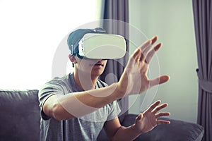 Young asian man wearing virtual reality glasses at living room for admiring virtual reality