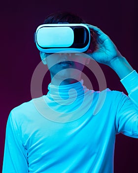 Young asian man wearing virtual reality goggles watching 360 degree video in neon light  Technology concept.