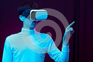 Young asian man wearing virtual reality goggles watching 360 degree video in neon light  Technology concept.