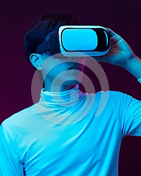 Young asian man wearing virtual reality goggles watching 360 degree video in neon light, Technology concept.