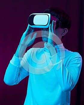 Young asian man wearing virtual reality goggles watching 360 degree video in neon light, Technology concept.