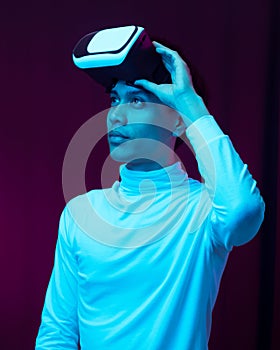 Young asian man wearing virtual reality goggles watching 360 degree video in neon light, Technology concept.