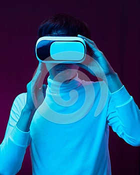 Young asian man wearing virtual reality goggles watching 360 degree video in neon light, Technology concept.