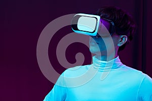 Young asian man wearing virtual reality goggles watching 360 degree video in neon light, Technology concept.