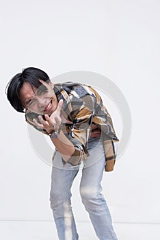 A young asian man winces in extreme pain, clutching his stomach. Cramped and hurting. Isolated on a white background