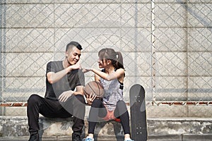 Young asian man and woman bumping fists outdoors photo