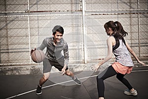 Young asian man and woman playing basketball for fun