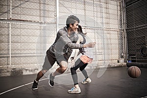 Young asian man and woman playing basketball for fun